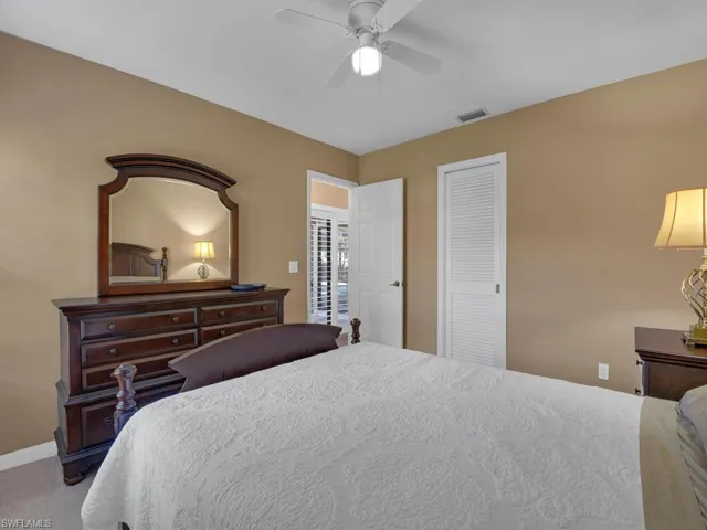 Carpeted bedroom featuring ceiling fan and a closet