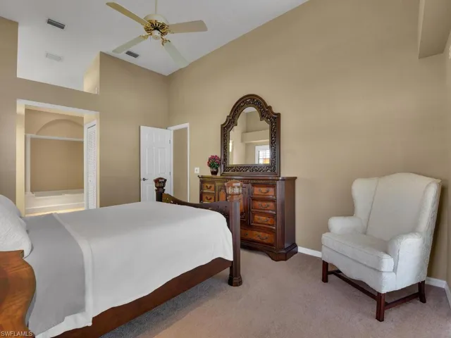Bedroom featuring vaulted ceiling, light colored carpet, and ceiling fan
