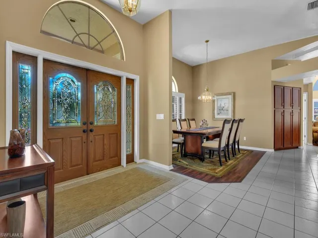 Entrance foyer with light tile patterned floors, a notable chandelier, and french doors