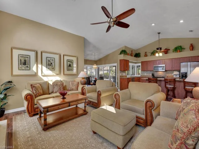 Living room with high vaulted ceiling, ceiling fan, and light hardwood / wood-style floors