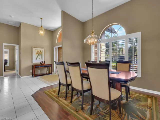 Tiled dining area with a high ceiling and an inviting chandelier