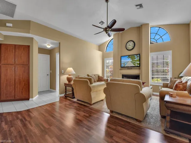 Living room featuring ceiling fan, high vaulted ceiling, and light wood-type flooring