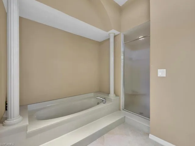 Bathroom featuring ornate columns, independent shower and bath, and tile patterned flooring
