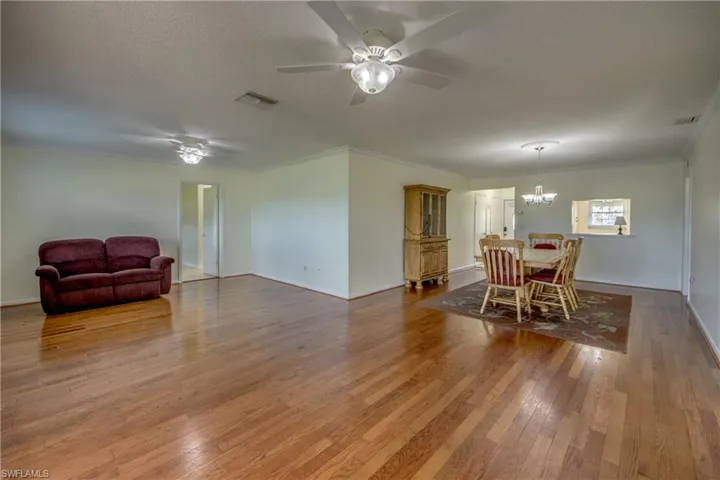 Dining area featuring hardwood / wood-style floors, ceiling fan with notable chandelier, a textured ceiling, and crown molding