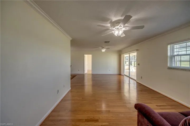 Spare room with plenty of natural light, light wood-type flooring, a textured ceiling, and ornamental molding