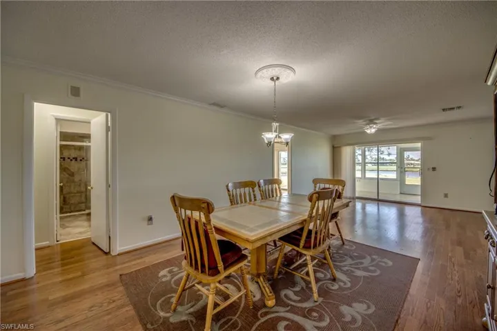 Dining space with crown molding, light hardwood / wood-style floors, a textured ceiling, and ceiling fan