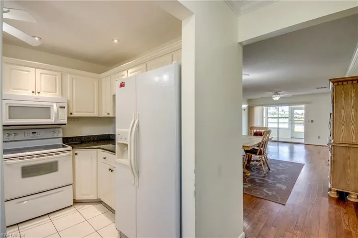 Kitchen with white cabinetry, ornamental molding, ceiling fan, white appliances, and light hardwood / wood-style flooring