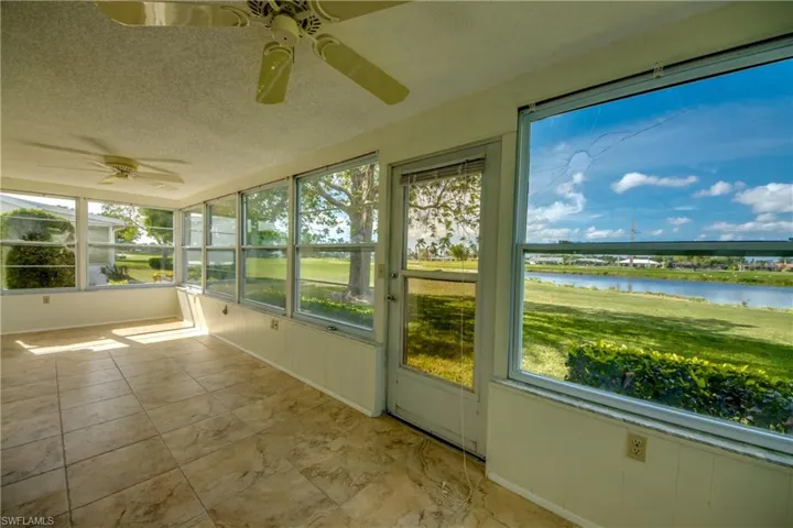 Unfurnished sunroom featuring a water view, ceiling fan, and plenty of natural light