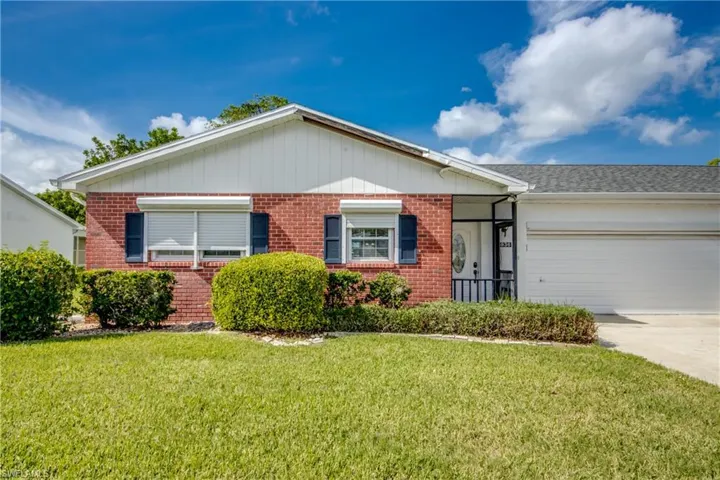 Ranch-style house with a garage and a front lawn