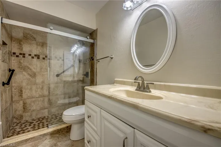 Bathroom featuring vanity, toilet, and a shower with door