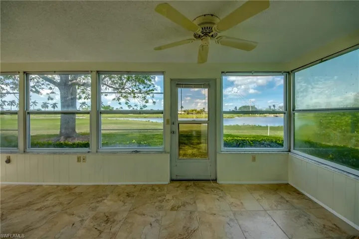 Unfurnished sunroom featuring ceiling fan and a water view