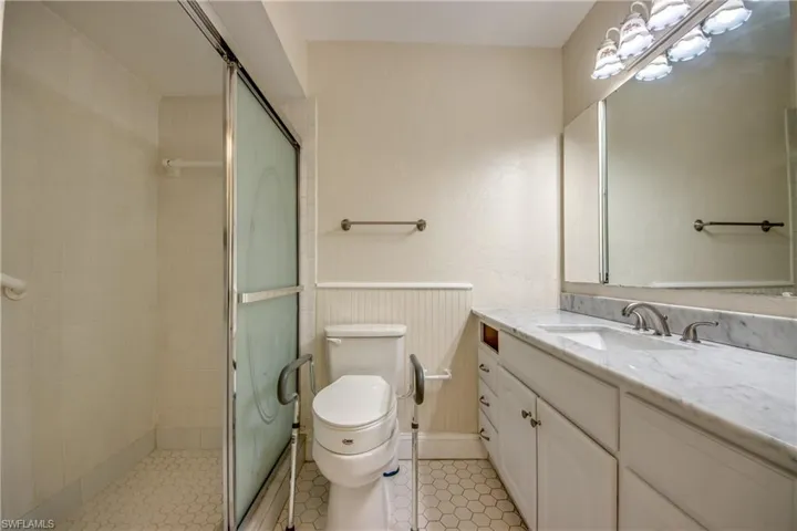 Bathroom featuring vanity, walk in shower, tile patterned flooring, and toilet