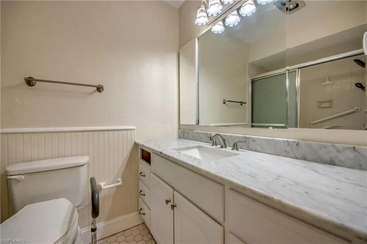 Bathroom with toilet, vanity, an enclosed shower, and tile patterned flooring
