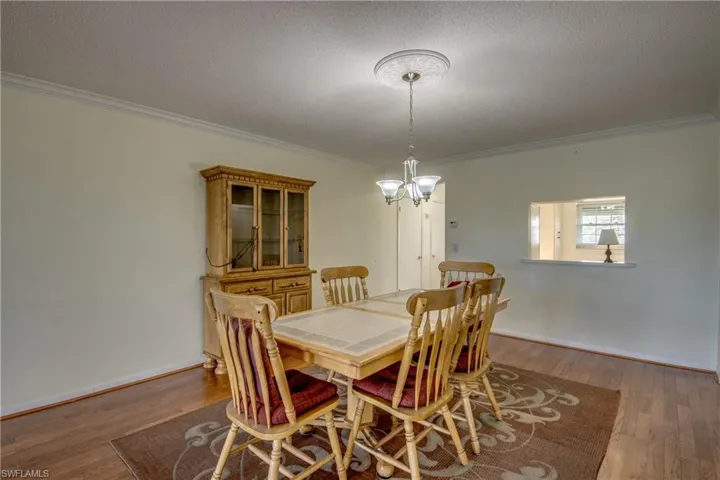 Dining space with hardwood / wood-style flooring, a textured ceiling, a notable chandelier, and ornamental molding