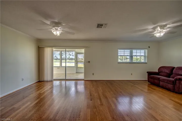 Unfurnished living room with hardwood / wood-style flooring, plenty of natural light, and crown molding