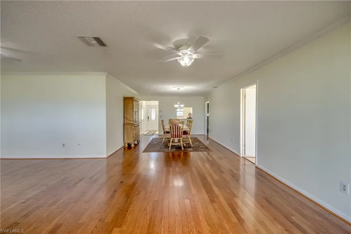 Unfurnished dining area featuring a textured ceiling, hardwood / wood-style flooring, ornamental molding, and ceiling fan with notable chandelier