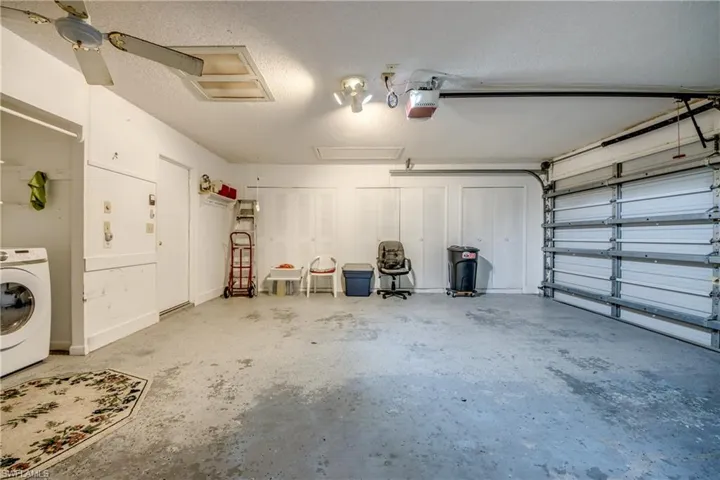 Garage with a garage door opener, washer / dryer, and ceiling fan