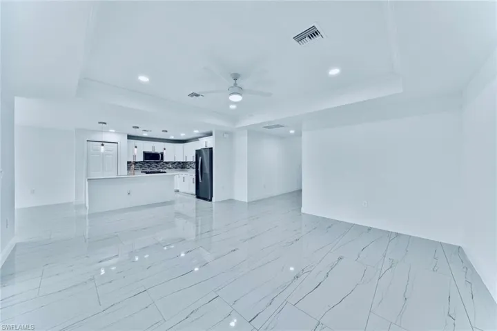 Unfurnished living room featuring ceiling fan, a raised ceiling, and crown molding