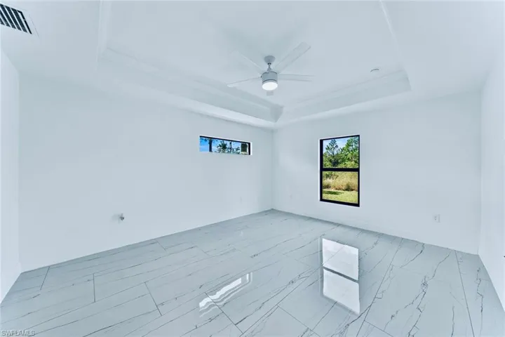 Empty room featuring crown molding, a tray ceiling, and ceiling fan