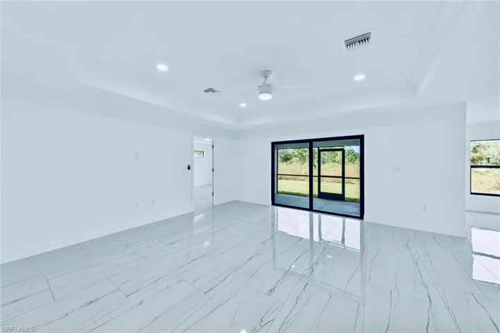 Unfurnished room featuring ceiling fan, a tray ceiling, and plenty of natural light