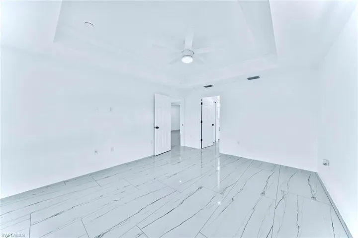 Empty room with ceiling fan and a raised ceiling