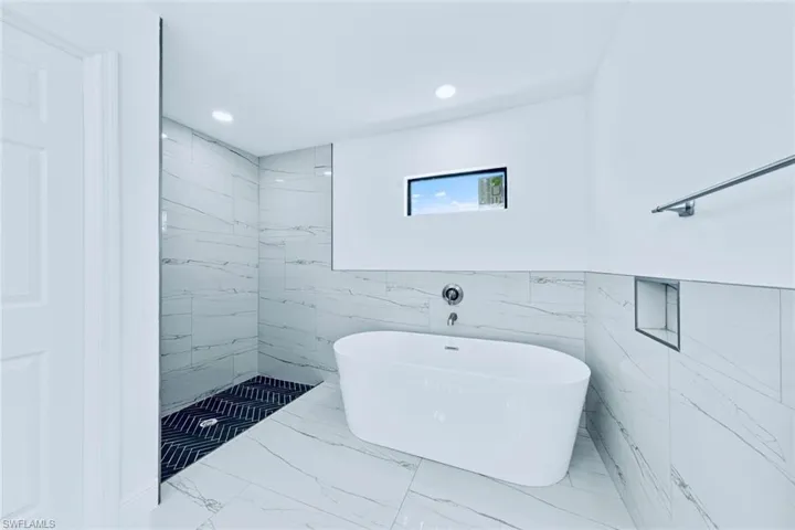 Bathroom featuring tile walls and independent shower and bath