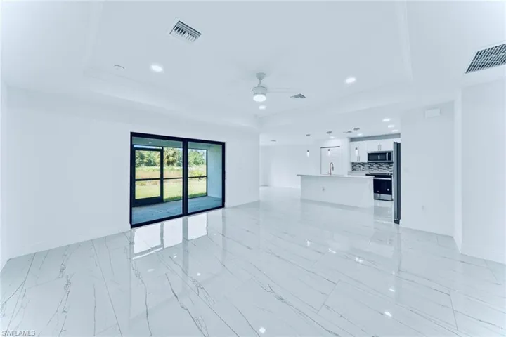 Unfurnished living room with ceiling fan, a raised ceiling, and crown molding