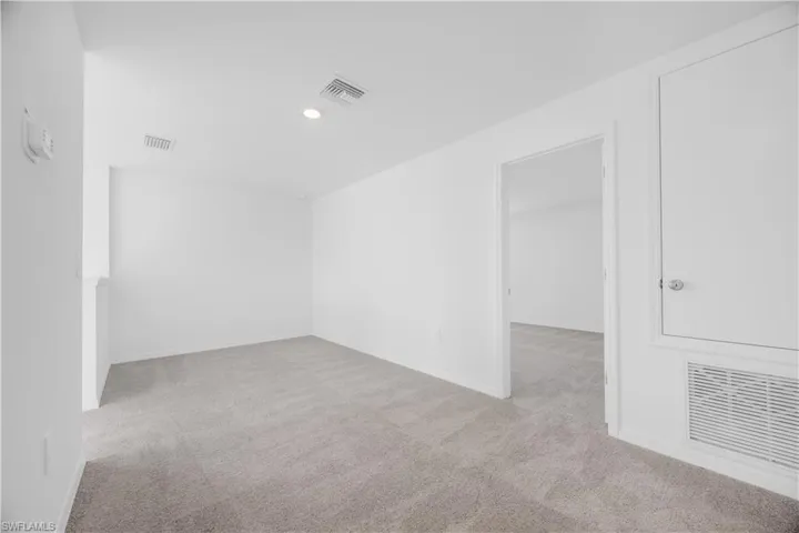 Carpeted room with white walls, recessed lighting, and an open doorway
