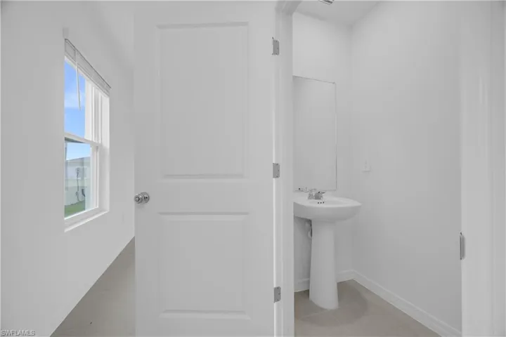 Pedestal sink with chrome fixtures and a wall-mounted mirror