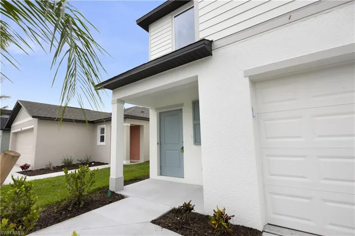 Contemporary stucco exterior with a light blue entry door, covered porch, and an attached garage