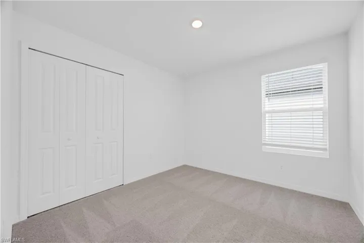 Neutral-toned wall-to-wall carpeting complements the bright white walls