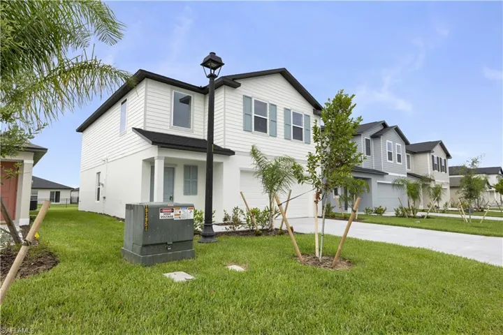 Two-story residence featuring a white and light blue exterior, dark shingle roofing, and a prominent front-facing garage