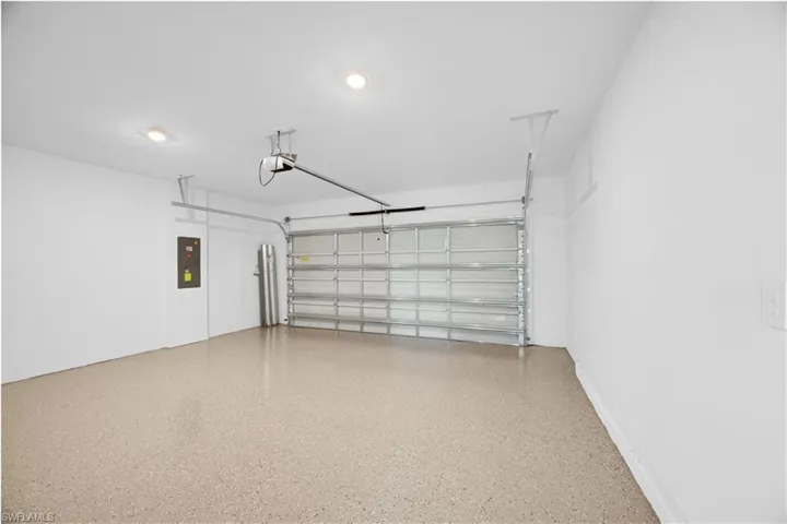 Spacious garage featuring a light-colored epoxy-coated floor, automatic overhead door, and recessed ceiling lighting