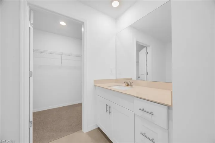 Vanity with a light-toned countertop, integrated sink, and white cabinetry featuring chrome hardware