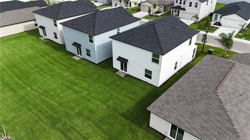 Expansive green space featuring manicured lawns surrounding newly constructed two-story homes with dark shingle roofing and light-colored siding