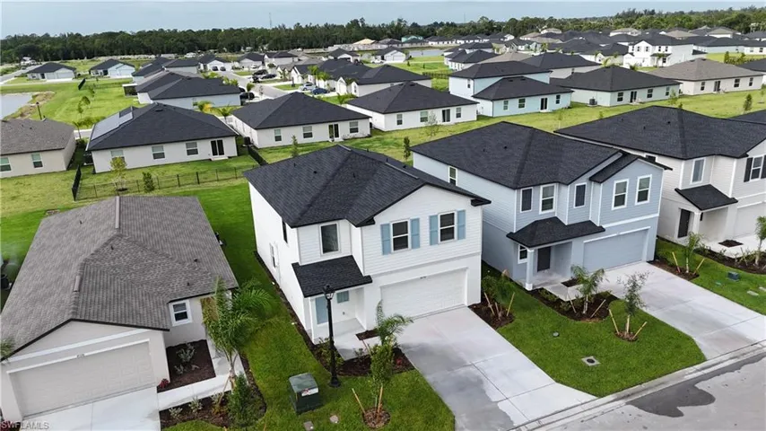Two-story residence featuring a two-car garage, manicured front lawn, and mature landscaping