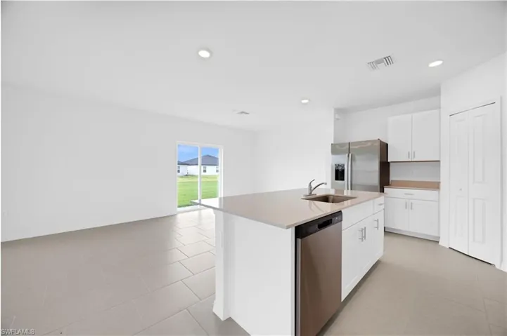 Open-concept kitchen featuring a central island with an undermount sink and stainless steel dishwasher