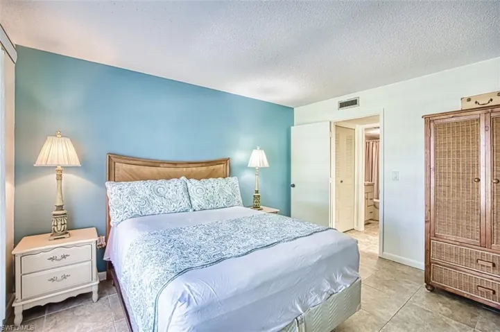 Bedroom with a textured ceiling, light tile patterned flooring, a closet, and connected bathroom
