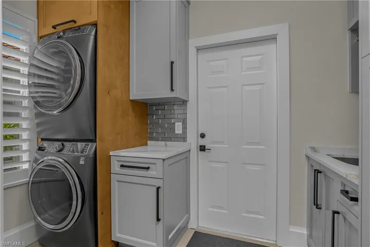 Storage cabinets in the renovated utility room...GE washer and dryer are full-sized stackable units, new in late 2024. Door leads to 2 car garage. Natural gas powers the 2025 water heater in the garage.
