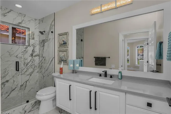 Guest full bath with frameless shower and quartz countertop.
