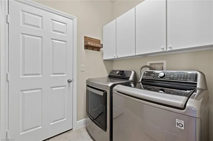 Laundry room featuring washing machine and dryer, washer hookup, light tile flooring, and cabinets