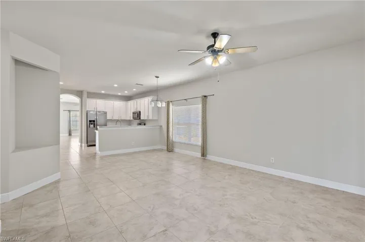 Unfurnished living room featuring sink, ceiling fan, and light tile floors