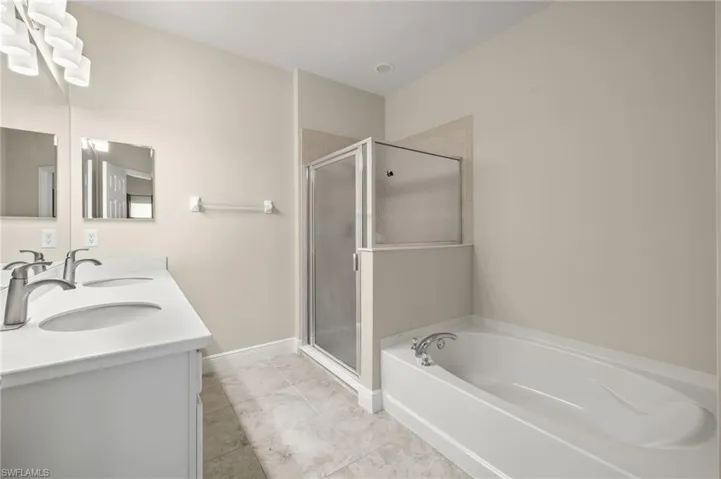 Bathroom featuring tile flooring, shower with separate bathtub, and dual bowl vanity