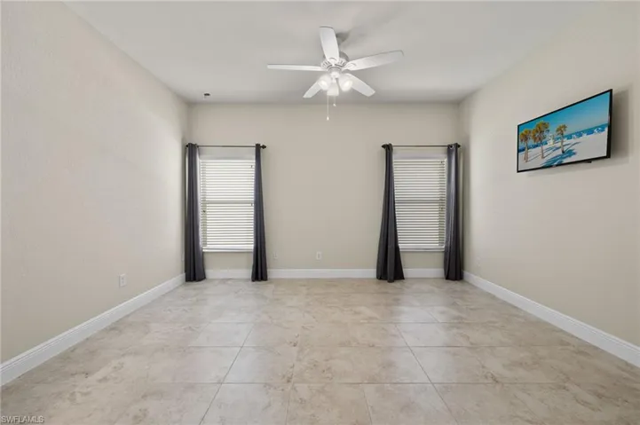 Unfurnished room with ceiling fan and light tile floors