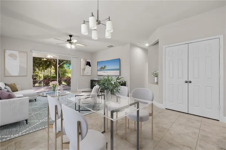 VS- Tiled living room with ceiling fan with notable chandelier