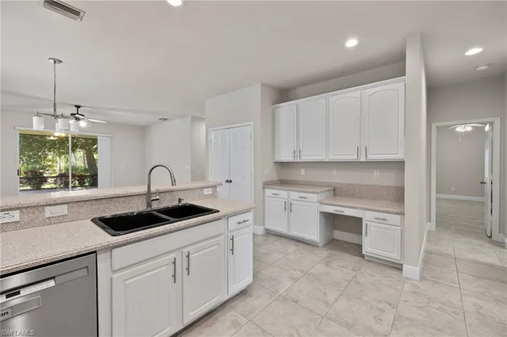 Kitchen with stainless steel dishwasher, white cabinets, sink, ceiling fan, and light tile floors