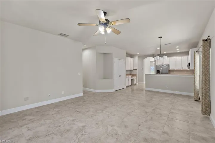 Unfurnished living room featuring ceiling fan and light tile floors