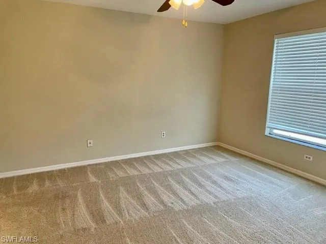 Empty room with a ceiling fan and light carpet