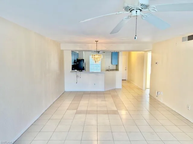 Unfurnished living room with ceiling fan, a chandelier, and light tile patterned floors