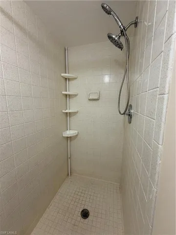 Walk-in shower with light-colored square wall tiles and smaller mosaic floor tiles